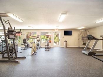 a gym with a lot of exercise equipment and a flat screen tv on the wall at Acacia Gardens, Albuquerque, New Mexico